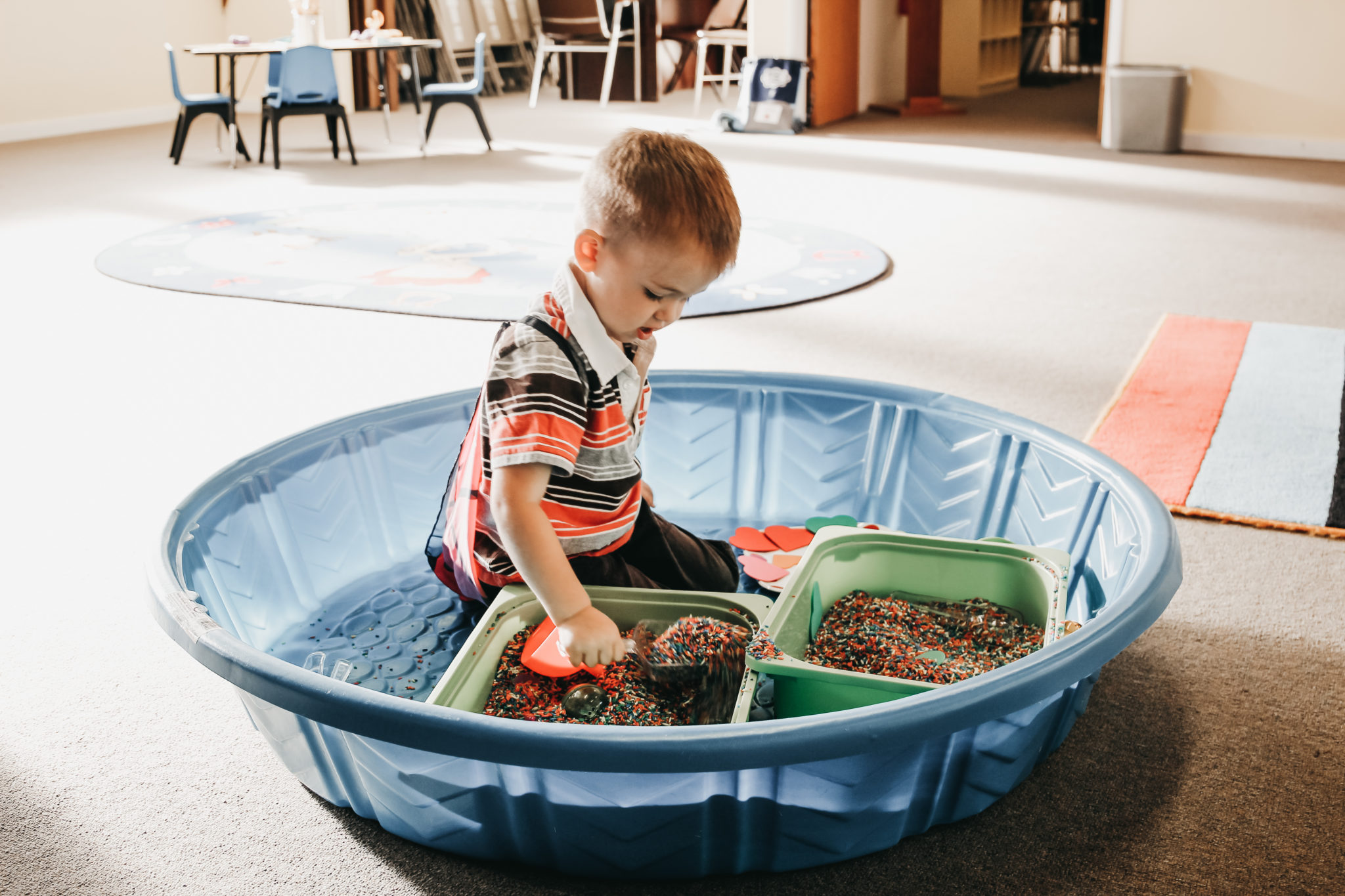 A boy playing in a tub with beads.